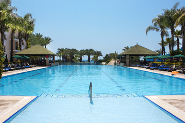 Fototapeta na wymiar View of the Mediterranean Sea, blue pool and palms