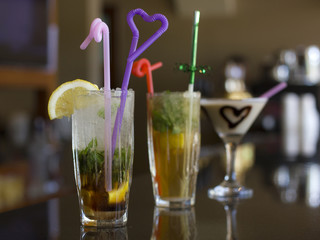 Three cocktails on the bar - Mojito with ice and straw, Pina Colada with chocolate heart