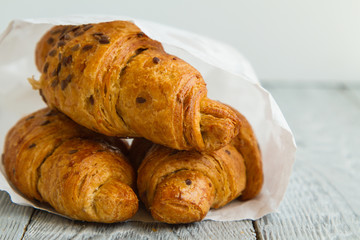 three delicious croissants in a white package on a white table