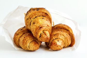 three delicious croissants in a white package on a white table