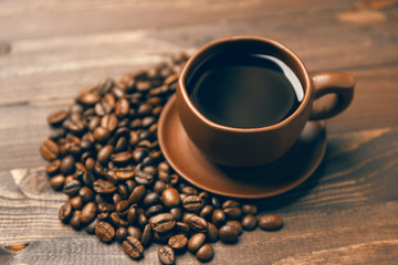 A cup of coffee and coffee beans on a wooden background