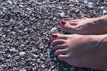 women's feet in the sea on a sandy beach