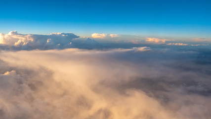 View of Large Clouds from Airplane with Sunset Sun reflecting on White Clouds