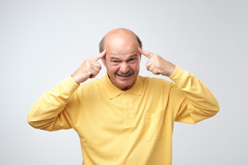 Displeased mature bald man is dissatisfied with hair loss.