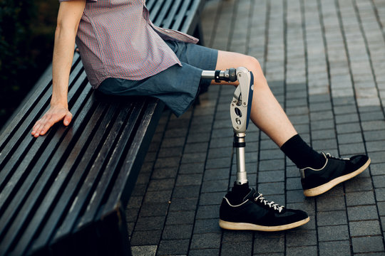 Disabled young man with foot prosthesis sitting outdoor