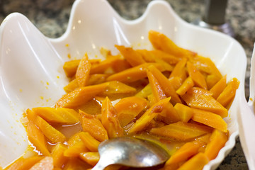 Boiled carrots in a white bowl with a spoon
