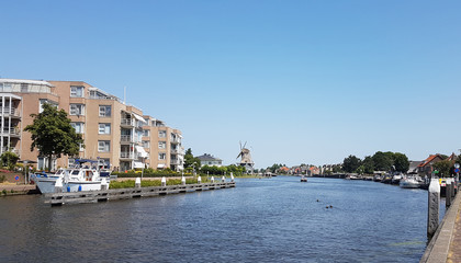 Fototapeta premium River Vliet in Leidschendam with blue sky and windmill Salamander on the background in the Netherlands.