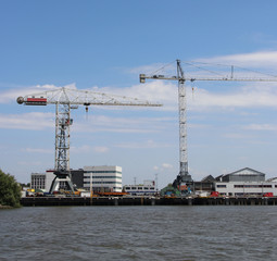 Obraz premium Docks with ships and cranes along the riverside of the river Lek or Noord in the Netherlands