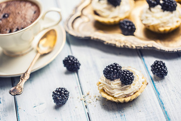 Mini tartlets with blackberries whipped cream and coffee.