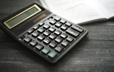 horizontal background with a calculator on a dark wooden surface of the table
