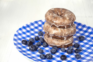 blueberry donut stack with berries on blue and white checked plate on wood