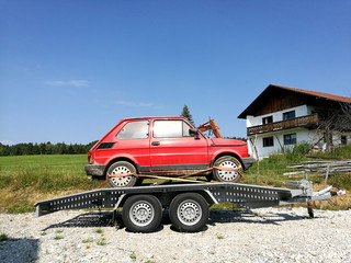 Alter roter italienischer Kleinwagen Klassiker auf einem Anhänger für den Transport im Sommer bei...