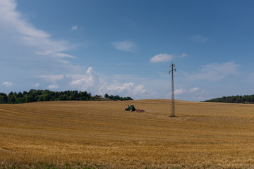 Fototapeta na wymiar Traktor auf Feld nach Strohenernte im Spätsommer