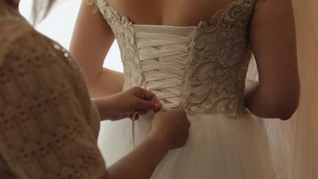 Wedding day. Bridesmaid tightens wedding corset