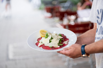 Rinder Carpaccio mit frisch gehobeltem Parmesan Käse und frischen Rucola auf einem teller und von...