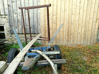 Altes Fahrgestell des Anhänger für den Traktor zum Holztransport vor der Holzfassade der Scheune...