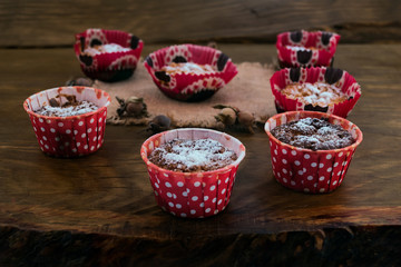 Fototapeta na wymiar Cookies of oat flakes with cottage cheese, cooked in the oven in paper forms of red, next to the hazelnut on a napkin of coarse cloth on a wooden background.