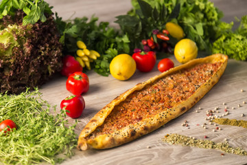 Adana Pide and tomato, lemon, lettuce,pepper and green vegetables on the wooden background for restaurant and cafe concept.