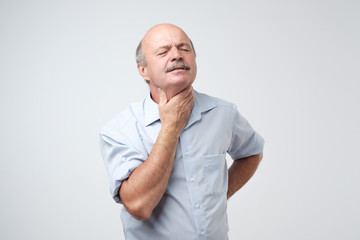 Mature man has a terrible pain in throat because of flu.