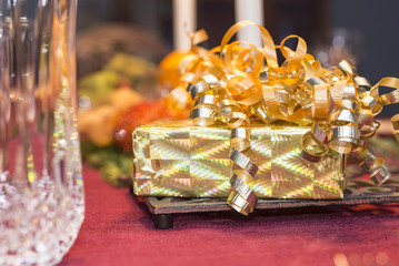 Gift wrapped box with curly ribbons on a holiday table.