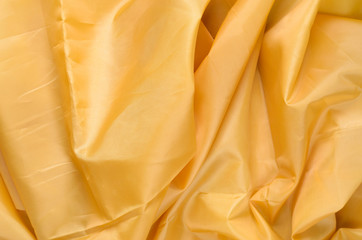 Yellow Synthetic Lining Fabric with Folds. Crumpled Sheet or Clothes Background,