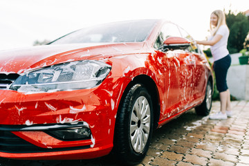 Young woman washing her car with sponge.