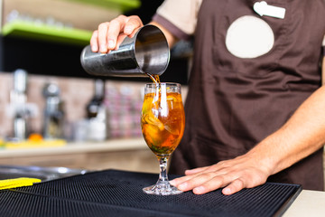 The bartender prepares cocktail at the bar.