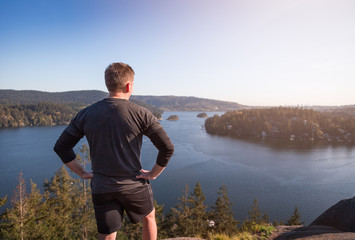 A jogger looking out from the top of a mountain onto the ocean.