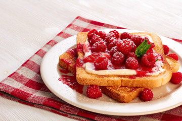 Toast with cottage cheese and raspberries on textile napkin