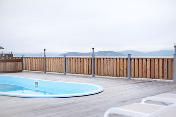 Fototapeta na wymiar Wooden deck beach sea ocean resort sun lounger umbrella hotel pool sky sunrise