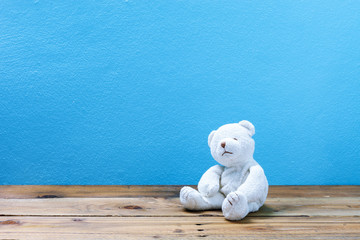 teddy bear on old wood ,blue wall background.