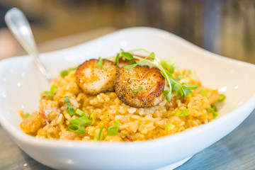 Tasty risotto with Gulf Shrimp, crawfish tails, seared scallops, fresh herbs vegetables on a white plate