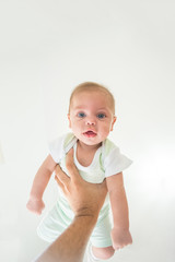 Blue eyed baby boy being lifted by father's arms - On white background