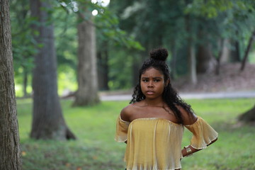 Pensive ethnic woman looking away in woods