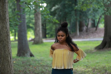 Pensive black woman in green woods