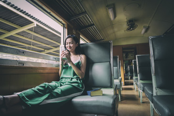 Asian woman traveler has drinking coffee in the train with happiness at Hua Lamphong station at Bangkok, Thailand.