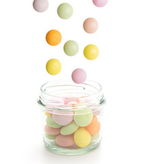 Colorful candies falling in jar isolated on white background.