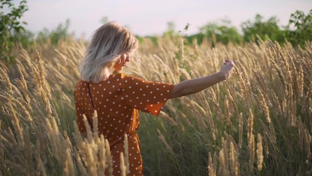 attractive fun hippie blonde woman in the field at sunset making a selfie with a bouquet