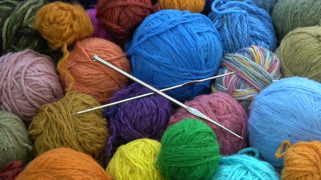 Rotating many  yarn wool balls with two metal knitting crotchets
