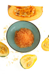  salt with pumpkin extract. Orange sea salt in a blue cup and slices of pumpkin isolated on white background.Pumpkin organic vegan cosmetics.