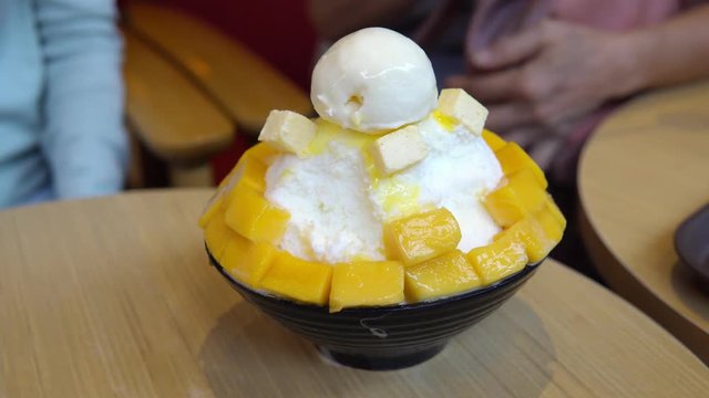 Group of people enjoy eating mango bing su, Korean dessert