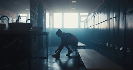 DOLLY IN Caucasian female athlete preparing for a workout in a gym locker room, tying shoelaces before training session. 4K UHD 60 FPS SLOW MOTION