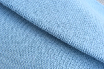 blue knitted fabric close-up soft fabric folds roll natural material background for decor blue color