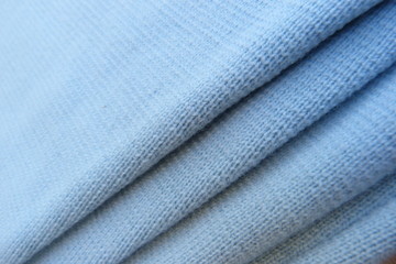 blue knitted fabric close-up soft fabric folds roll natural material background for decor blue color