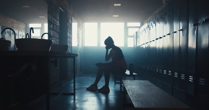 DOLLY IN Caucasian female athlete preparing for a workout in a gym locker room, putting on earphones and choosing music on her phone. 4K UHD 60 FPS SLOW MOTION