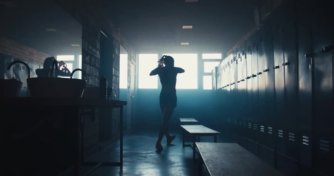 DOLLY IN Caucasian female athlete taking off shirt in a gym locker room, angry, not satisfied with her workout results. 4K UHD 60 FPS SLOW MOTION