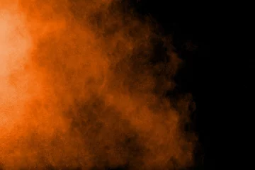 Foto op Canvas Abstracte oranje poederexplosie op zwarte achtergrond. Bevriezen beweging van oranje stofdeeltjes spatten. © Pattadis
