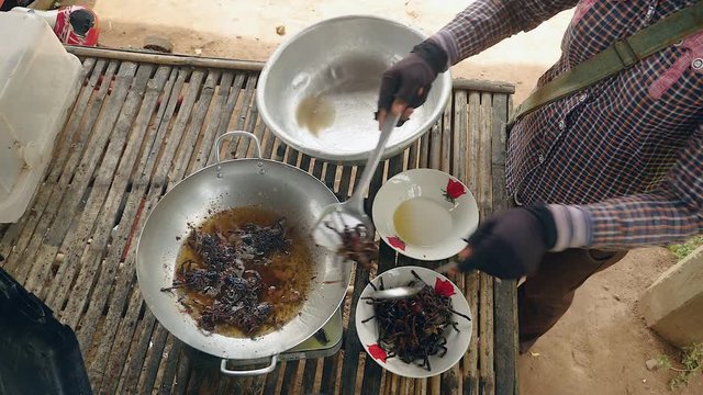 Woman plunging dead tarantulas into boiling oil for cooking ( upper view)