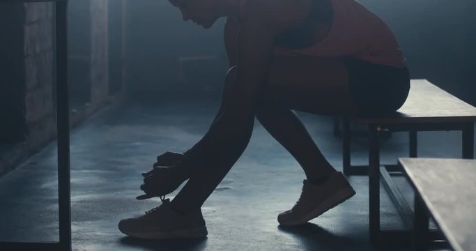 CU DOLLY IN Caucasian female athlete preparing for a workout in a gym locker room, tying shoelaces before training session. 4K UHD 60 FPS SLOW MOTION
