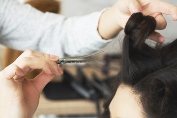 Fototapeta premium Closeup view of the hairstylist hand combing a new hairstyle on a customer head in hair salon.